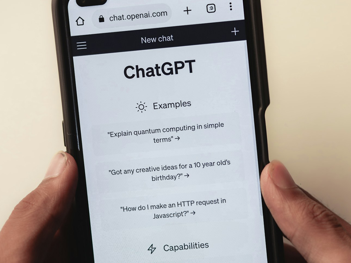 A phone showing the default example prompts in a chat assistant - explain a concept simply, ideas for a child's birthday, a basic coding question - the everyday tasks that make up most real AI use